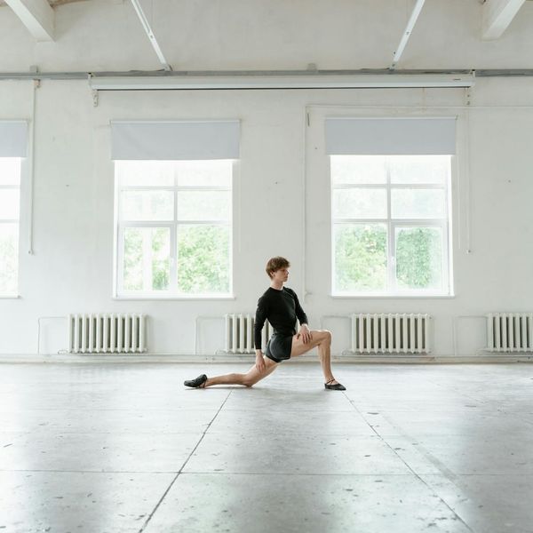 Man stretching his legs in a bright, minimalist studio.